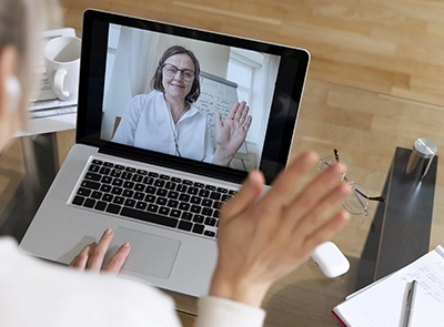 imagem de uma pessoa dando tchau para outra, que está em vídeo-chamada, na tela do notebook